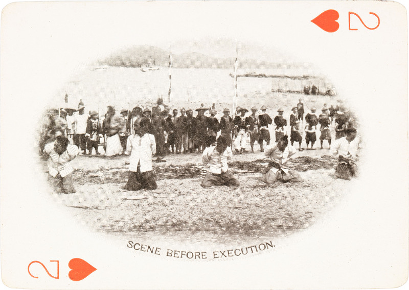 The 2 of hearts with a picture of 5 men on the beach kneeling with a large crowd behind them.