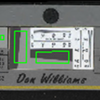 Gray rectangular bar oriented horizontally with gray slanted rectangles outlined in green near the center, dots on the edges, and squares of colors and white, gray and black values aligned from left to right that have corresponding numerical values printed under them (LAB colorspace values) with little green outlined squares within them, the green squares a product of the target being measured for FADGI compliance by software.
